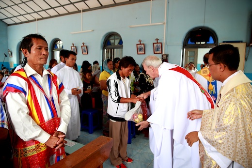 Mark Raper SJ receiving offertory at first vows of new Jesuits in Myanmar