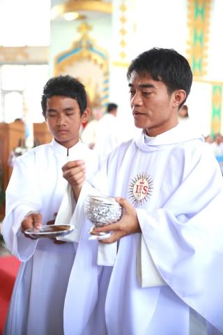 Newly ordained Wibert Mireh SJ gives communion at his ordination mass